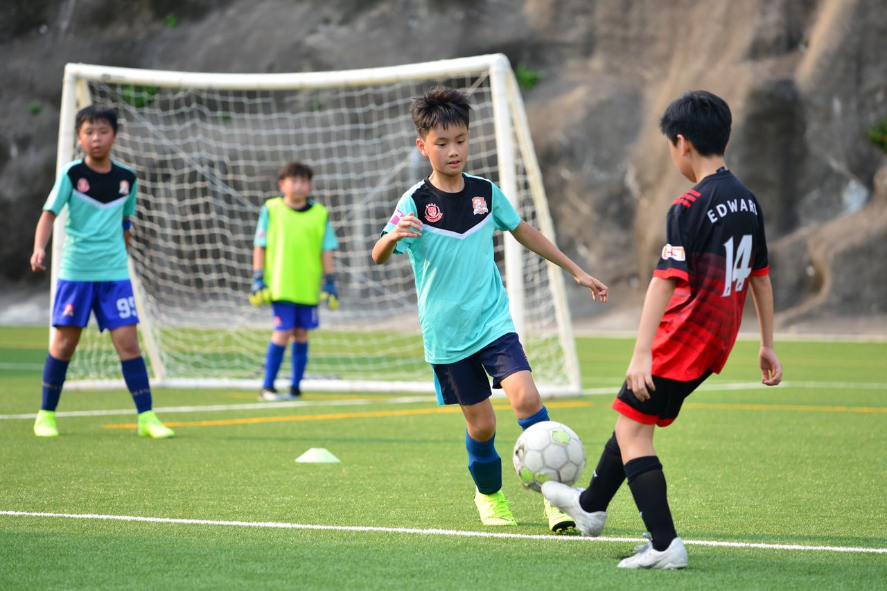 About Boys playing soccer during a team training session outdoors on a sunny day.