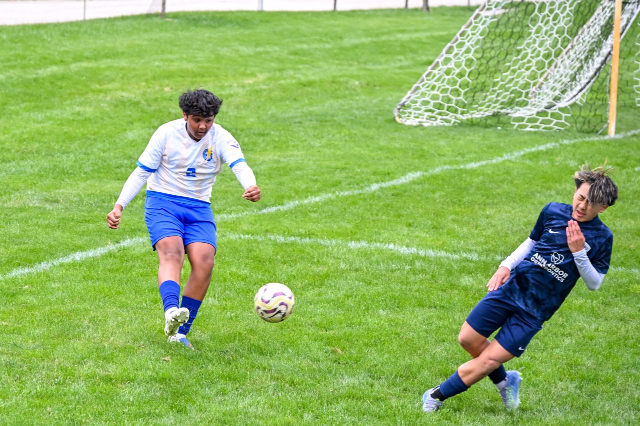 Services Intense soccer match with two teenagers battling for the ball on a green field.
